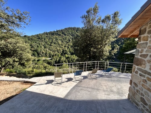 Mountain view terrace at Gîte Les Oliviers d'Ardèche with seating overlooking forested hills in Chalencon