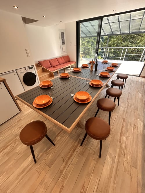 Modern dining area in Gîte Les Oliviers d'Ardèche with mountain views, orange tableware, and brown chairs