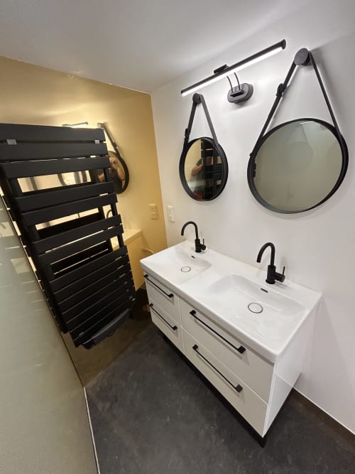 Modern bathroom in Gîte Les Oliviers d'Ardèche cottage with dual sinks, black fixtures, heated towel rack, and round mirrors