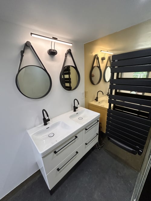 Modern bathroom in Gîte Les Oliviers d'Ardèche cottage with double sink, black mirrors, heated towel rail, and warm lighting