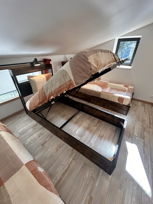 Gas-lift bed with brown bedding in attic bedroom at Gîte Les Oliviers, Chalencon