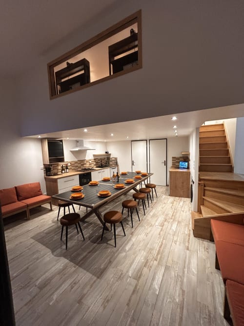 Modern dining area in Gîte Les Oliviers d'Ardèche cottage with black table, brown chairs, and orange accents