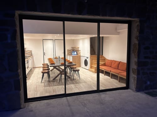 Modern cottage interior at Domaine du Chambonnet showing open-plan living with dining area, kitchen, and orange sofa in