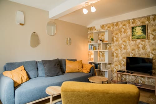 Salon moderne du cottage Mi Casa Es Su Casa à Carcassonne avec canapé bleu, accents jaunes et vue sur les monuments