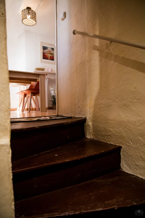 Escalier aux marches en bois sombre menant à une pièce lumineuse du gîte Mi Casa Es Su Casa, Carcassonne
