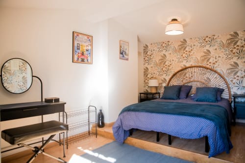 Chambre lumineuse du gîte La Petite Vue à Carcassonne avec lit en rotin, papier peint botanique et équipements modernes