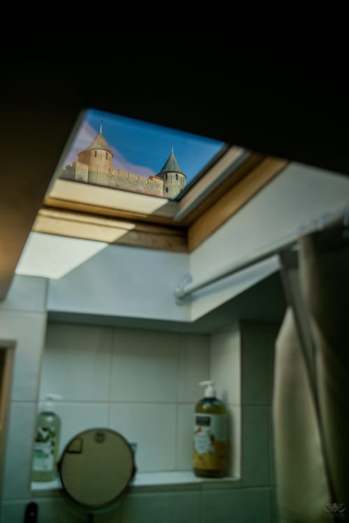 Châssis de puit de lumière dans la salle de bain encadrant la vue sur la forteresse de Carcassonne, gîte La Petite Vue, hôtel Carcassonne