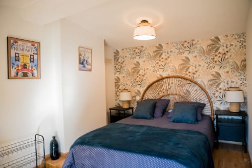 Chambre accueillante au gîte Mi Casa Es Su Casa à Carcassonne avec papier peint floral, tête de lit en rotin et literie bleue