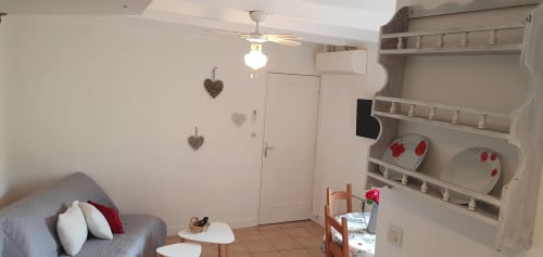 Studio cosy à Carcassonne avec canapé, étagères, ventilateur et cœurs décoratifs au mur