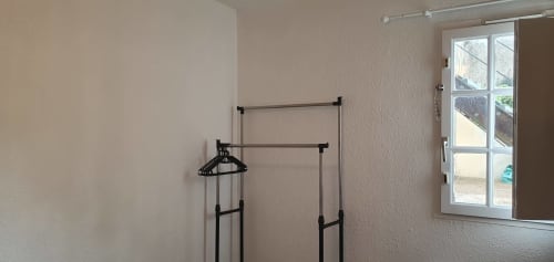 Chambre minimaliste avec portant à vêtements et fenêtre sur le jardin à l'appartement Mi Casa Es Su Casa à Carcassonne