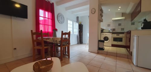 Cuisine ouverte avec salle à manger dans un appartement de Carcassonne, touches de rouge, électroménagers modernes et vue sur le jardin