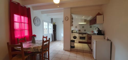 Cuisine ouverte et lumineuse avec salle à manger dans un appartement de Carcassonne, rideaux rouges, table en bois et appareils modernes