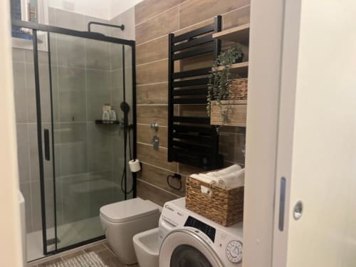 Bagno moderno con doccia a filo pavimento, wc e lavatrice nell'appartamento A Casa di Imma a Milano, vicino Bocconi e Duomo