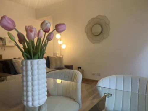 Elegante appartamento a Milano con tulipani viola in vaso bianco, sedie raffinate e illuminazione calda vicino a Bocconi