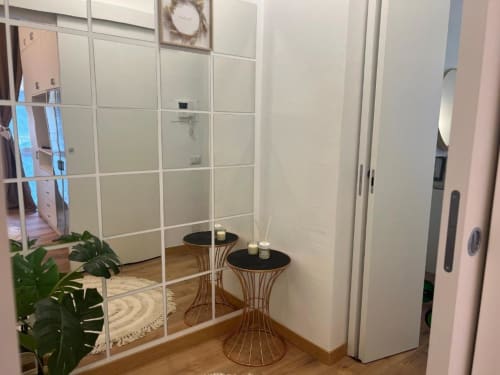 Ingresso moderno di A Casa di Imma Milano con parete specchiata, tavolini in legno e porte scorrevoli bianche