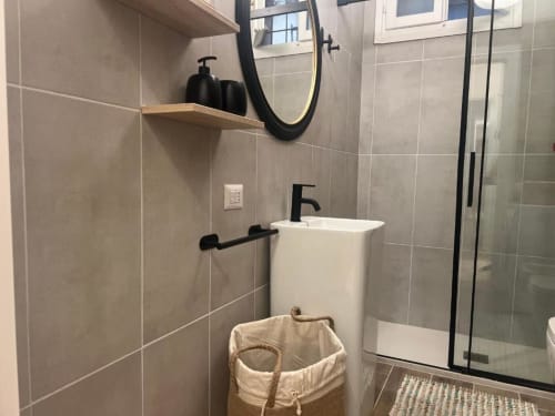 Bagno moderno dell'appartamento A Casa di Imma Milano con lavabo a colonna bianco, rubinetteria nera e box doccia in vetro