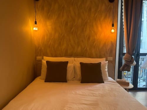 Camera da letto moderna di A Casa di Imma a Milano con illuminazione dorata calda, carta da parati contemporanea e luci pendenti
