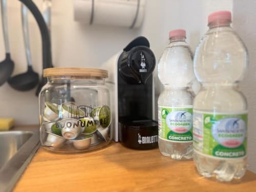 Piano cucina dell'appartamento a Milano con bottiglie d'acqua, macchinetta del caffè e barattolo di conservazione
