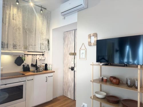 Monolocale moderno a Milano con cucina compatta, credenza bianca, piano in legno, scaffalatura e