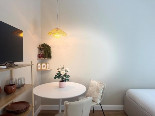 Monolocale moderno a Milano con tavolo rotondo bianco, lampada a sospensione e pianta vicino al letto - Camera design Navigli