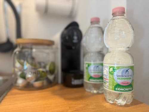 Bottiglie d'acqua San Benedetto e amenities su tavolo in legno in appartamento a Milano vicino ai Navigli e al Duomo