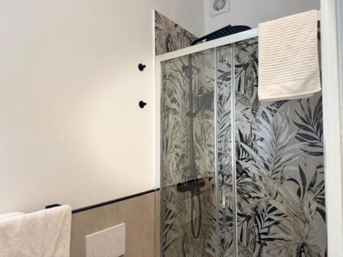 Moderna cabina doccia con piastrelle a motivi botanici nel bagno dell'appartamento A Casa di Imma a Milano