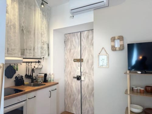 Cucina moderna dell'appartamento milanese con mobili bianchi, top in legno e arredo minimalista vicino ai Navigli e al Duomo