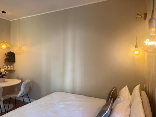 Camera da letto moderna a Milano con luci a sospensione, biancheria bianca, scrivania e illuminazione calda vicino al Navigli