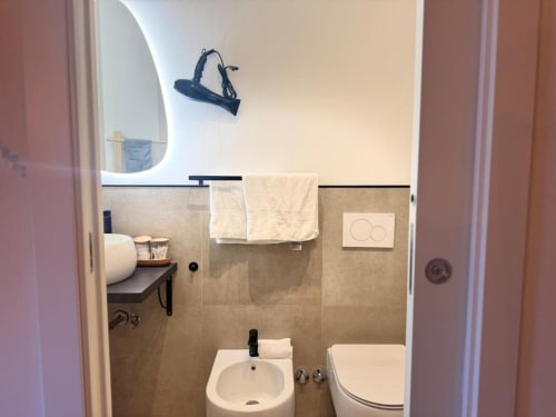 Bagno moderno in appartamento a Milano vicino al Duomo con lavabo, toilette, portasciugamani, specchio e piastrelle beige
