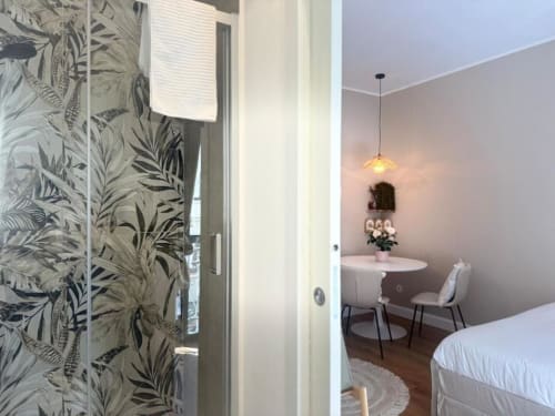 Camera da letto in moderno appartamento milanese con porta in vetro botanico, lampadario a sospensione e zona di lavoro vicino Navigli e Duomo