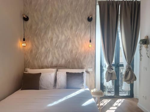 Camera da letto di moderno appartamento milanese con carta da parati di design, luci a sospensione e terrazza con vista sulla città vicino ai Navigli