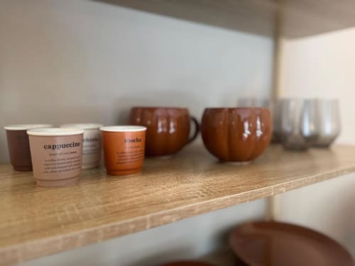 Tazze di caffè e tazze di ceramica esposte su una mensola in legno nell'appartamento A Casa di Imma a Milano