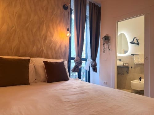 Camera da letto moderna dell'appartamento A Casa di Imma Milano con bagno ensuite, illuminazione a sospensione e vista sulla città vicino ai Navigli