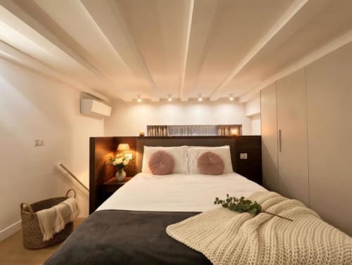 Camera moderna dell'appartamento A Casa di Imma a Milano con letto queen, cuscini decorativi, testata scura e illuminazione ambientale