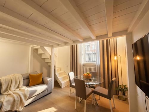 Loft moderno in famiglia nel Fashion District di Milano con spazi aperti, travi a vista, divano, zona pranzo e luce naturale