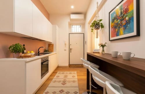Cucina moderna in A Casa di Imma Milano vicino ai Navigli con ante bianche, rivestimento arancione, piano in legno e bancone
