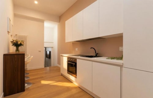 Cucina moderna bianca con pavimenti in legno nell'appartamento Family Loft presso A Casa di Imma, Milano Fashion District