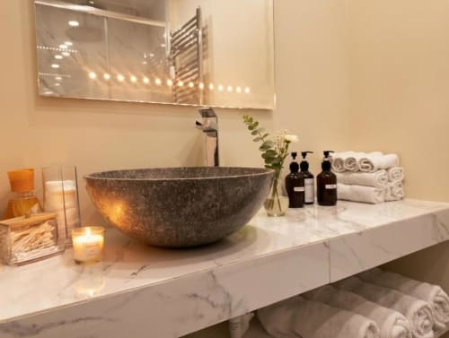 Lussuoso mobile bagno di A Casa di Imma Milano con piano marmoreo, lavabo in pietra e servizi spa
