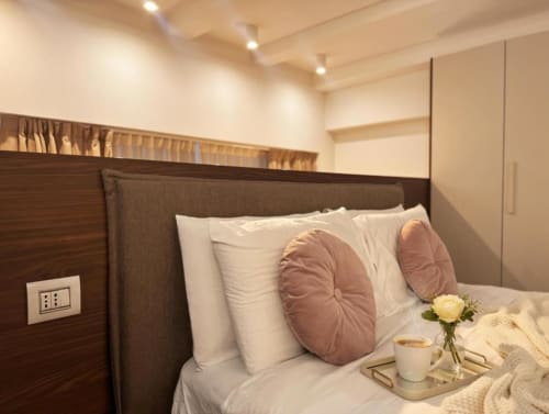 Camera elegante ad A Casa di Imma Milano con testata in legno, biancheria bianca, cuscini in velluto rosa e rose gialle