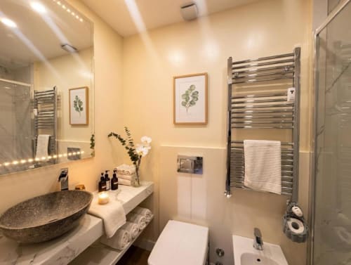 Bagno moderno nell'appartamento A Casa di Imma a Milano con lavabo da appoggio, scaldasalviette e decorazioni botaniche