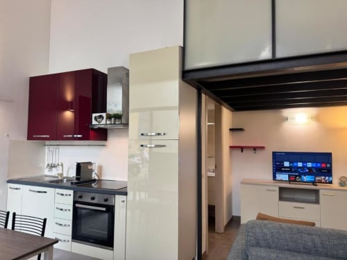 Cucina open-plan moderna e zona living ad A Casa di Imma Family Loft a Milano con armadi bordeaux e unità color crema