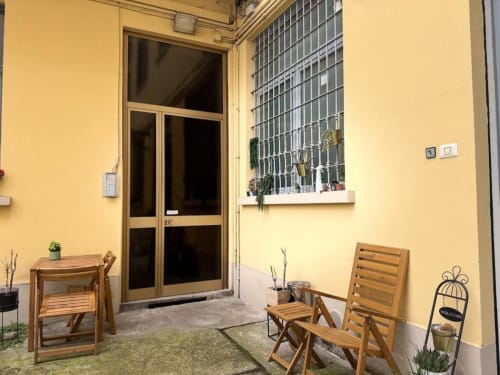 Tranquillo cortile interno dell'appartamento A Casa di Imma Milano con sedie lounge in legno e piante in vaso