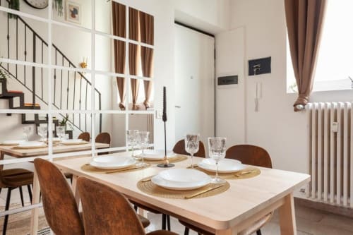 Zona pranzo in loft familiare presso A Casa di Imma Milano con tavolo apparecchiato, sedie moderne e scala per la mezzanine