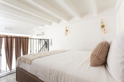 Camera da letto in stile loft moderno presso A Casa di Imma Milano con travi bianche, biancheria neutra, applique dorate e accesso al balcone