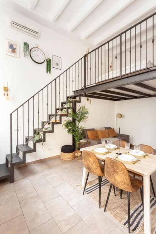 Zona pranzo del loft milanese moderno con tavolo in legno, scala a soppalco e piante d'appartamento presso A Casa di Imma