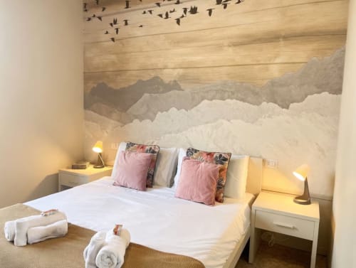 Camera moderna ad A Casa di Imma Milano con murale montano, letto bianco, cuscini rosa e illuminazione calda