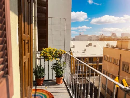 Balcone soleggiato dell'appartamento milanese con fiori in vaso, vista sulla città e cielo azzurro presso A Casa di Imma vicino a Bocconi