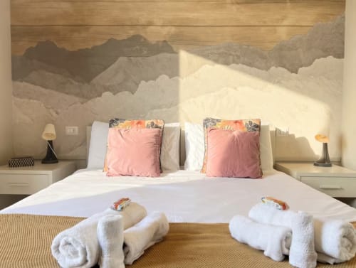 Luminosa camera da letto in appartamento milanese con murale montano, letti gemelli, cuscini rosa e asciugamani arrotolati presso A Casa di Imma