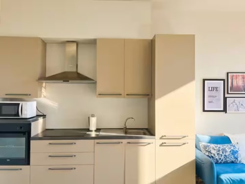 Cucina moderna dell'appartamento A Casa di Imma Milano vicino a Bocconi, con mobili color crema, piano di lavoro scuro e acciaio inox