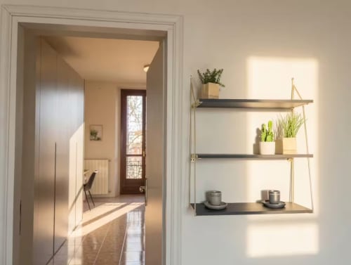 Ingresso moderno di appartamento a Milano con libreria, piante in vaso e luce naturale vicino a Bocconi